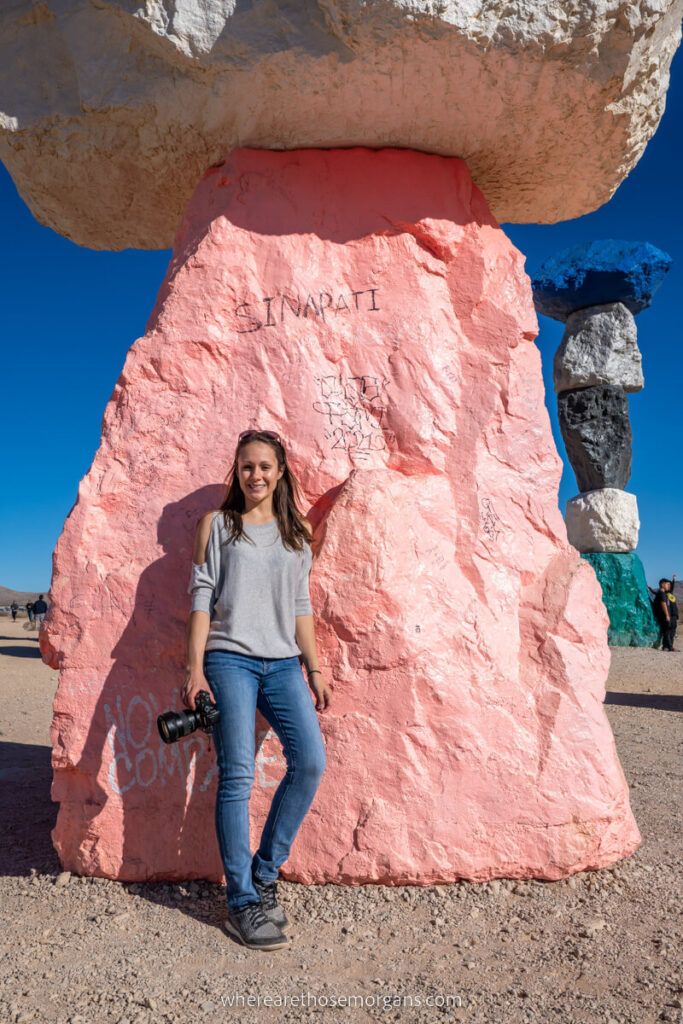 Photographer posing against a pink colored boulder