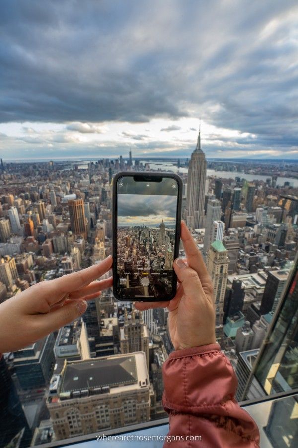 Woman holding out an iphone to take a photo of the Empire State Building