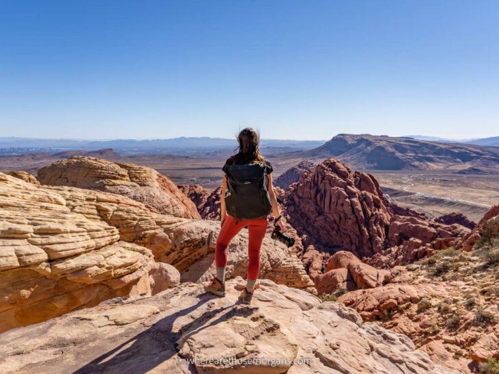 Best Hikes in Red Rock Canyon near Las Vegas Kristen from Where Are Those Morgans enjoying the views from Calico Tanks summit holding camera looking out at the desert