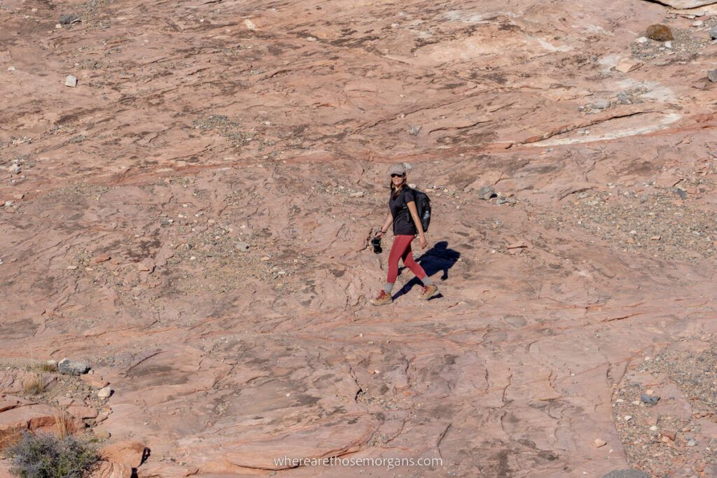 Hiker with camera walking on red sandstone rocks in Nevada