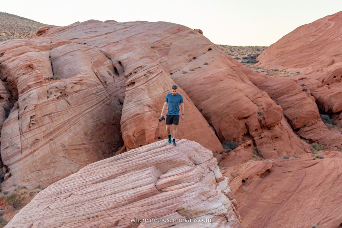 Hiker with camera walking to the top of a dome shaped rock formaiton