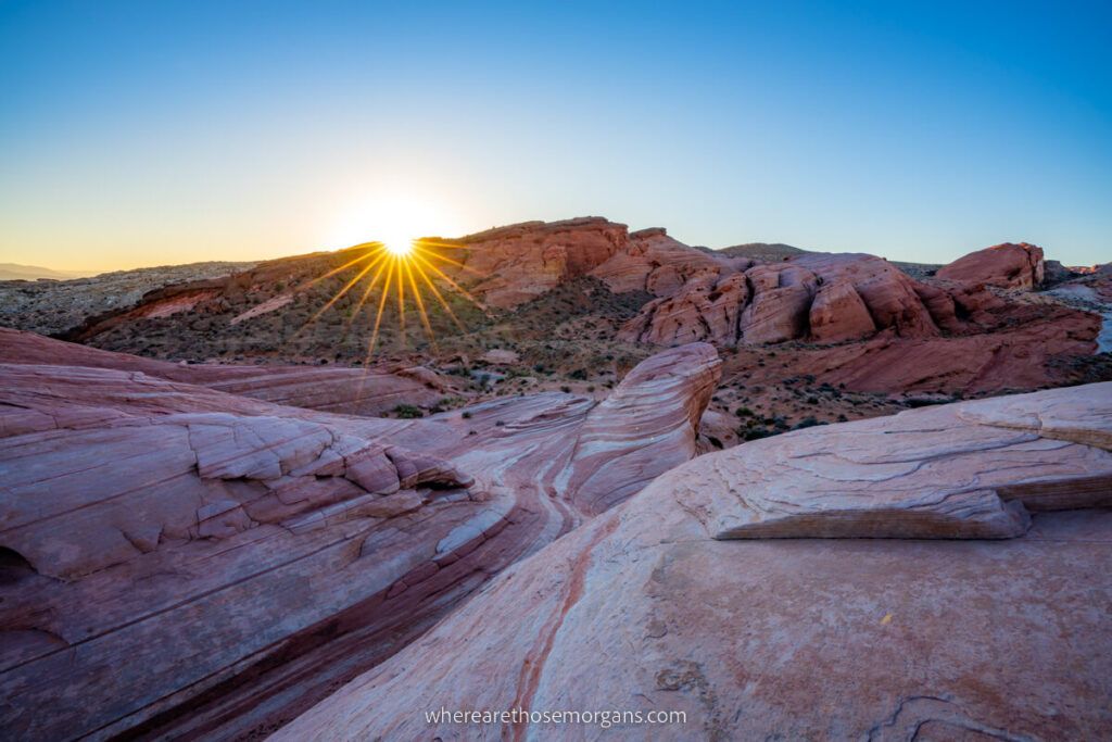 Sunrise at the Fire Wave hiking trail in Valley of Fire with sun starburst and vibrant red colored rocks