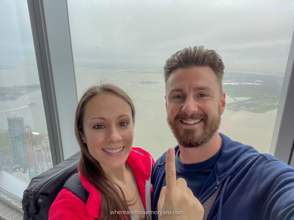 Man and woman pointing to the State of Liberty from One World Observatory
