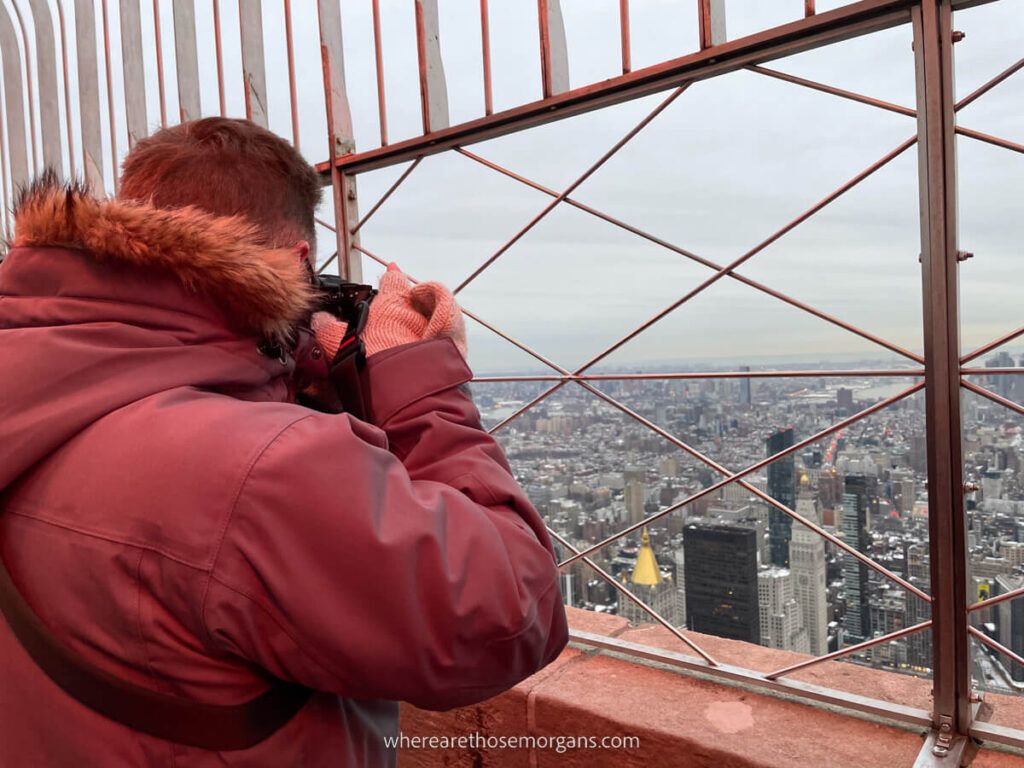 Man taking a photo through metal fencing at a NY observation deck