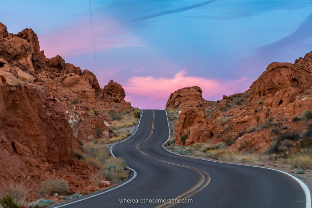 Valley of Fire highway narrow paved road cutting through red rock formations at sunset with pink and blue sky