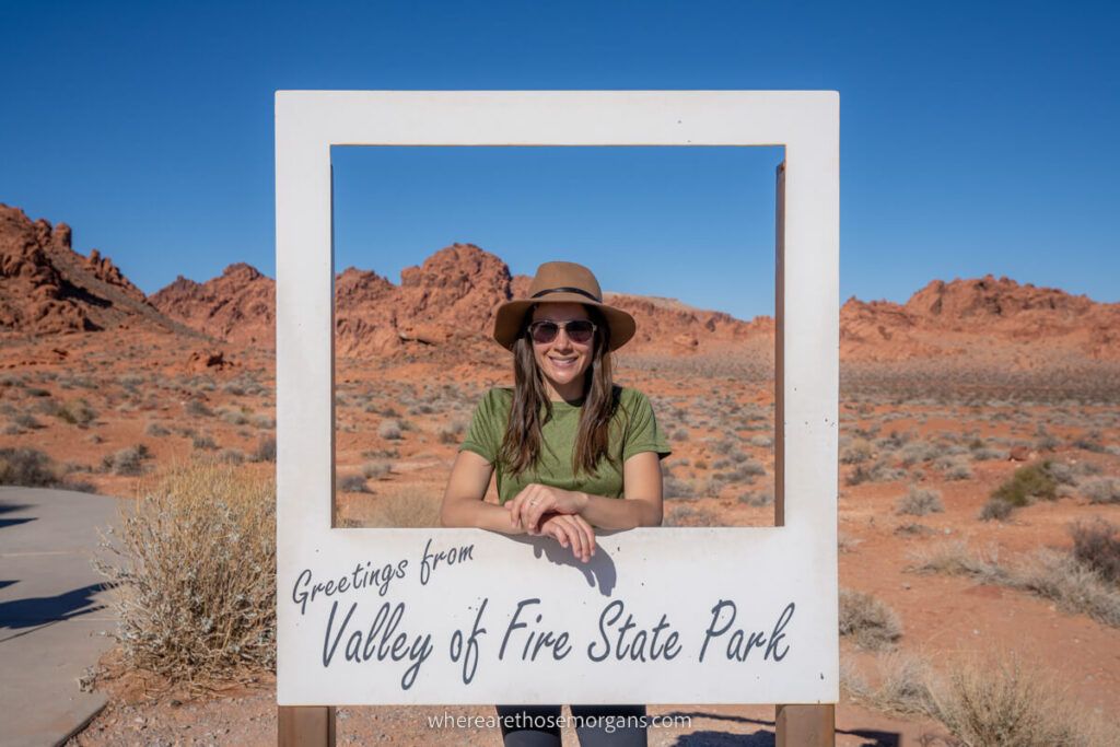 Woman smiling through a cut out polaroid picture frame with greetings from Valley of Fire State Park near Las Vegas in Nevada