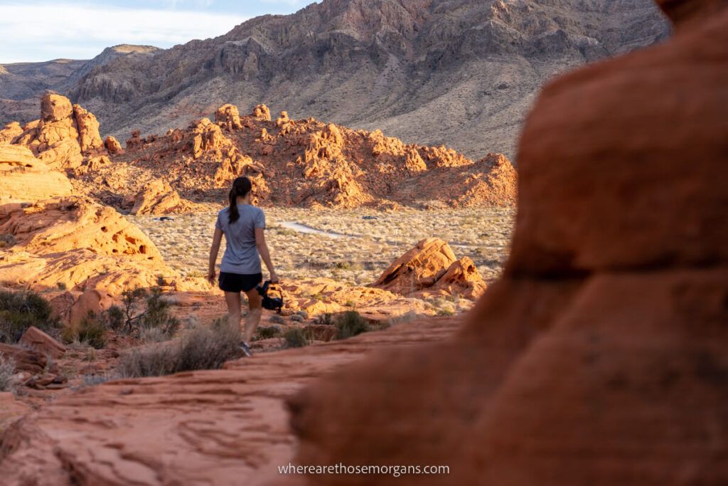 Woman hiking on red rocks in late afternoon with shadows and sun contrasting slightly in Nevada
