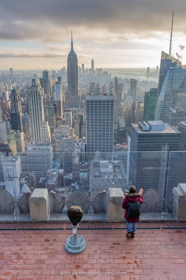 Woman leaning on the glass at Top of the Rock observation deck in New York City looking into Manhattan