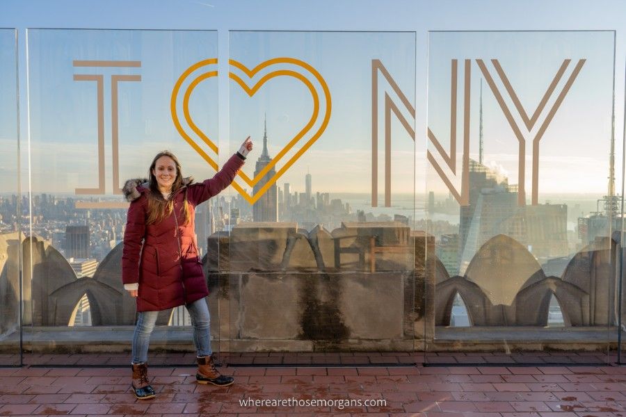 Woman pointing to Empire State Building and I Love NY sign