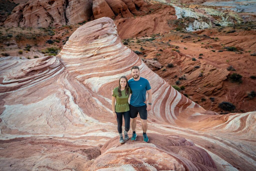 Mark and Kristen from Where Are Those Morgans standing together on a red and white striped rock formation called Fire Wave in Valley of Fire near Las Vegas Nevada before sunrise