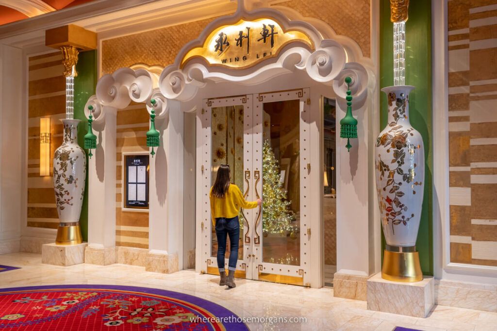 Woman opening a door leading into Wing Lei Chinese restaurant in Wynn Hotel elaborate facade