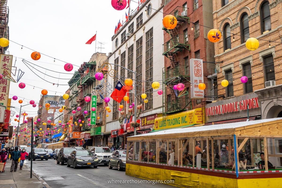 Colorful lanterns hanging across the road with restaurants and cars parked in Chinatown NYC
