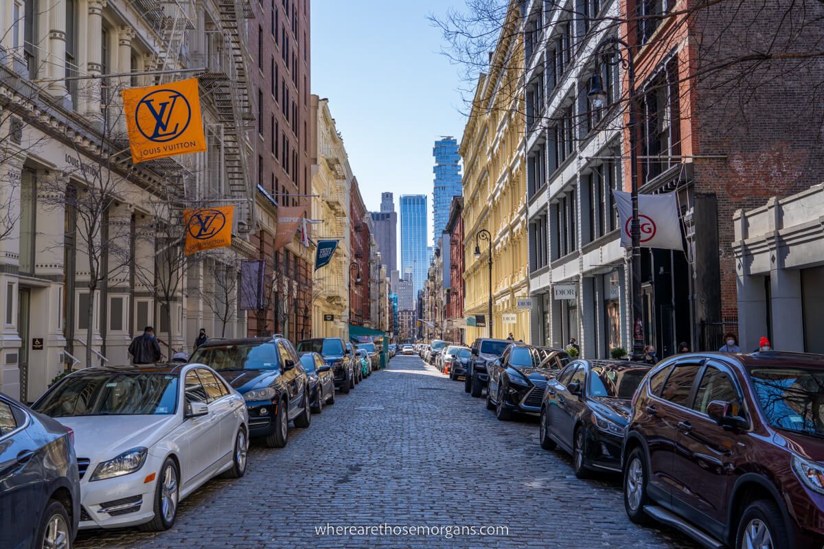 SoHo New York street with cobbled bricks and cars parked along narrow row of shops one of the popular places for tourists to visit in NYC