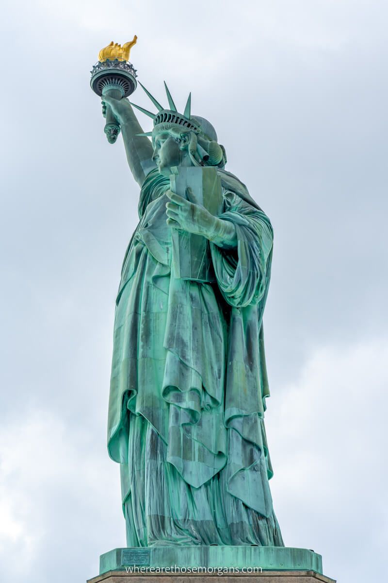 Close up of the Statue of Liberty holding torch aloft from below and to the side in nyc
