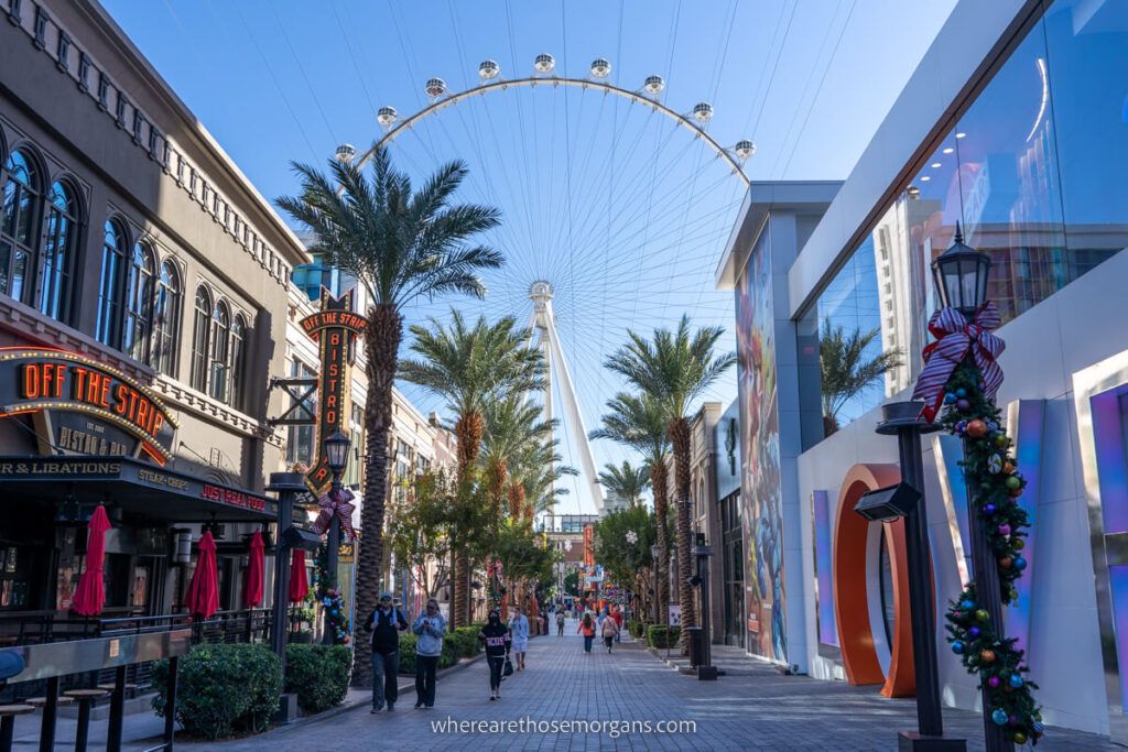 The High Roller wheel slowly turning behind row of restaurants and bars in Las Vegas on a cool November morning