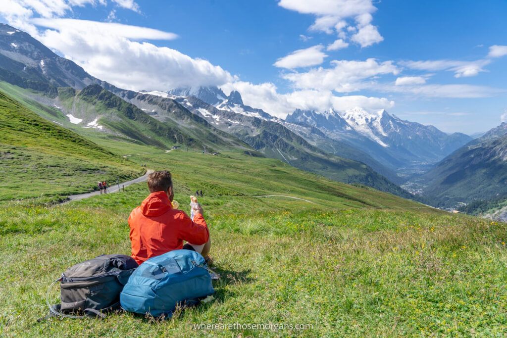 Man sitting on the top of a mountain with the Osprey Farpoint 40L backpack