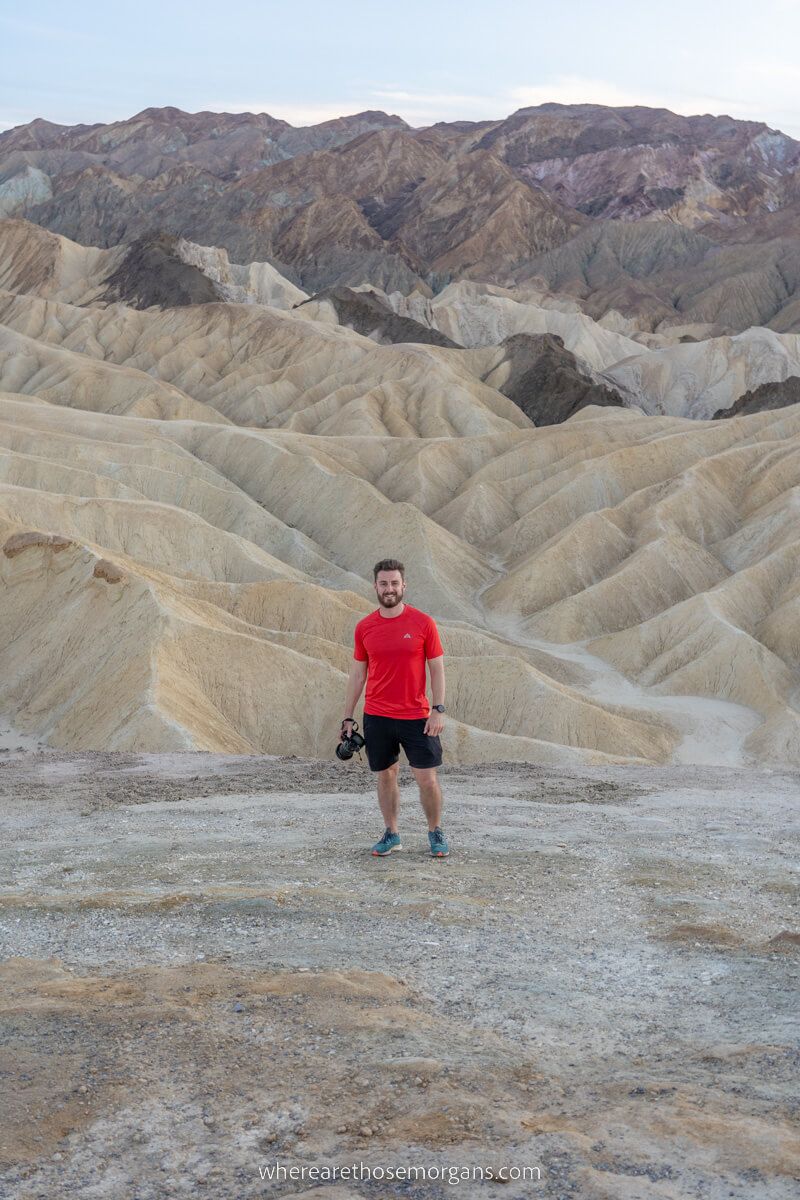 Photographer in red t-shirt contrasting against the soft yellow colors of Death Valley mounds at dusk
