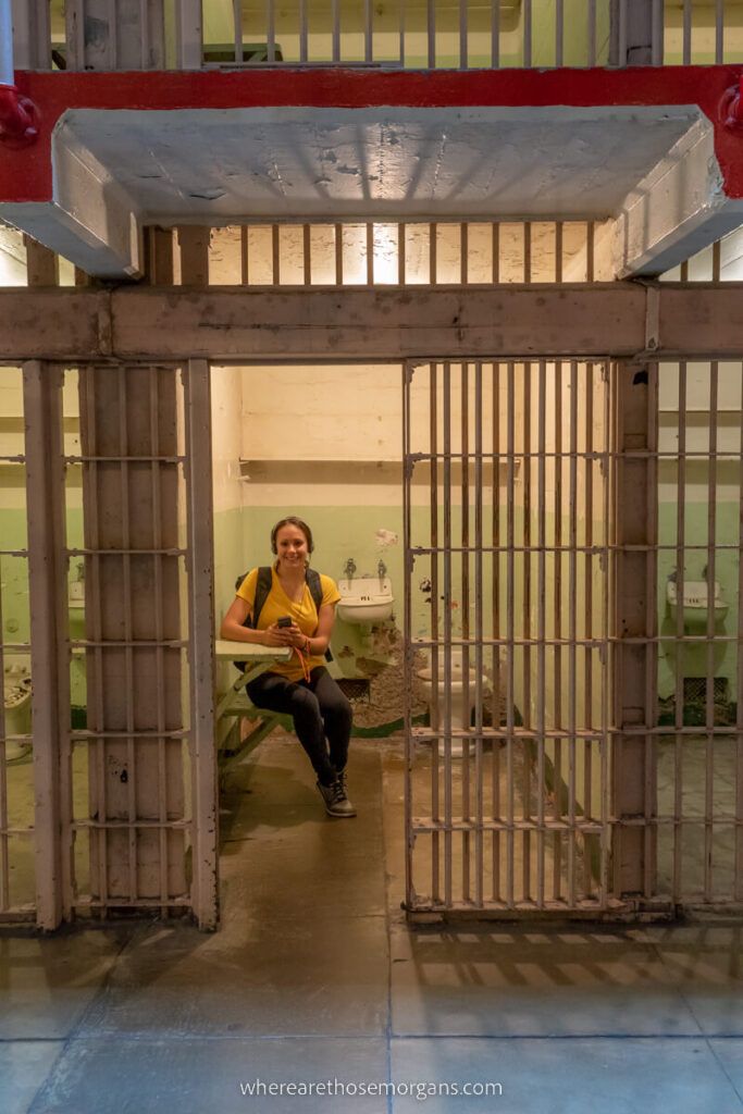 Woman sitting in an empty cell of Alcatraz prison