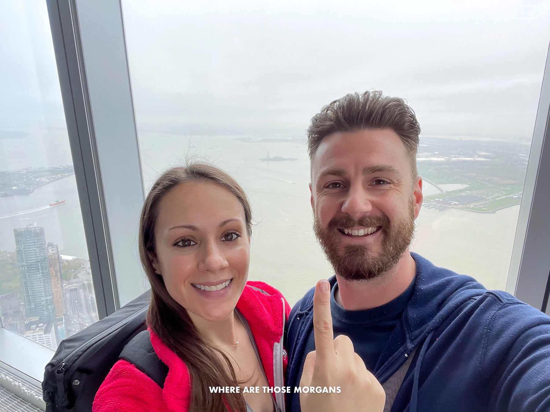 Mark and Kristen from Where Are Those Morgans taking a selfie at the top of One World Observatory with Kristen pointing up at the clouds shrouding the view