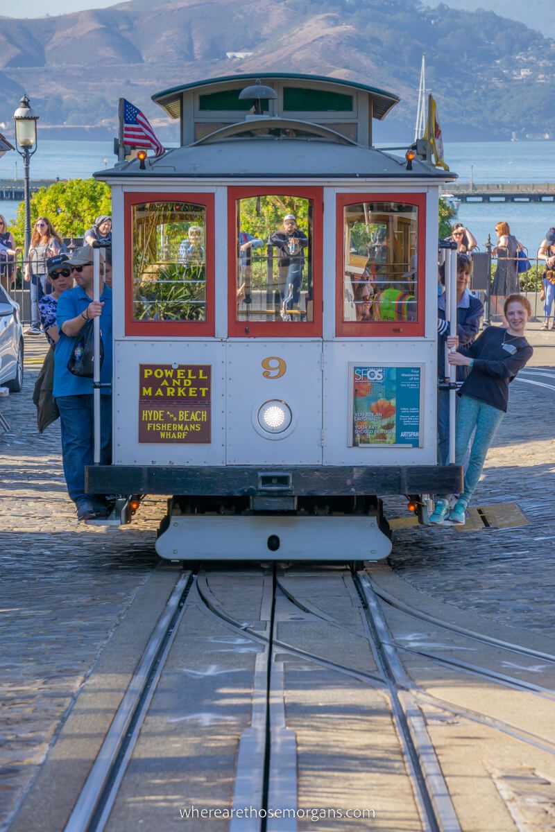 People hanging off the side of a cable car in San Francisco California one of the best things to do on a first visit to SF