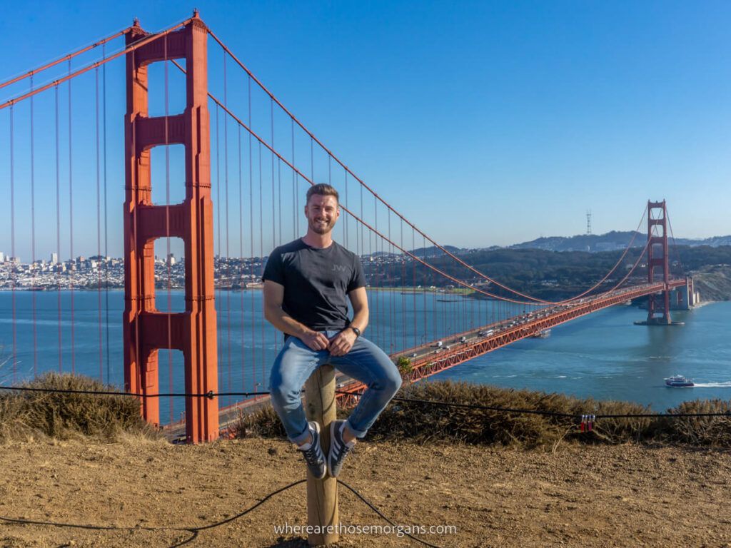 Man sat on wooden pole at Marin Headlands with Golden Gate Bridge in background