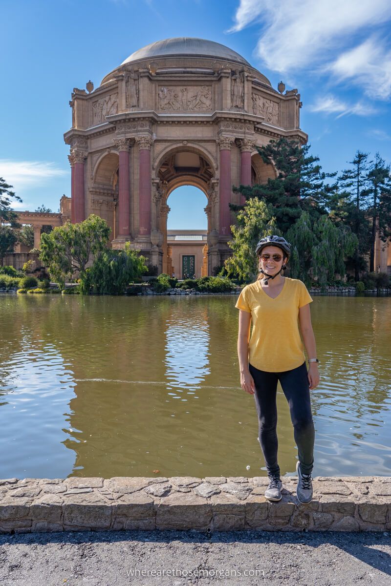 Palace of Fine Arts in SF with cyclist wearing helmet stood in front of lagoon