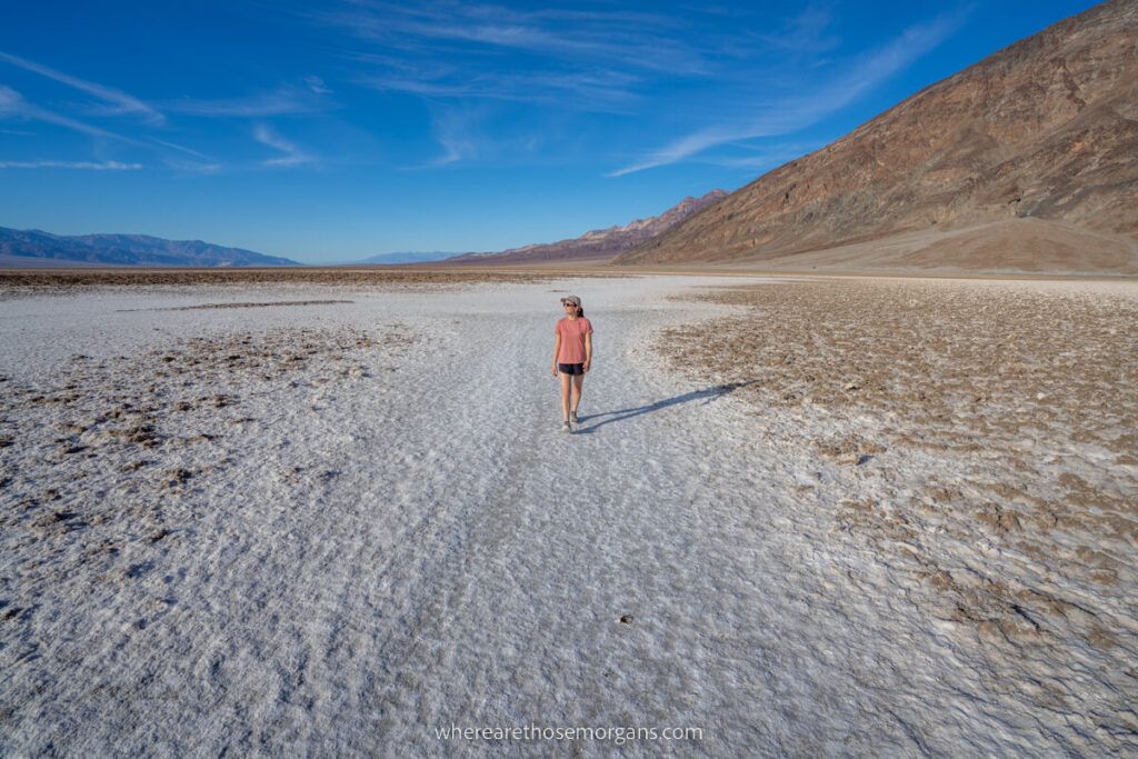 Woman walking on Badwater Basin salt flats with blue sky
