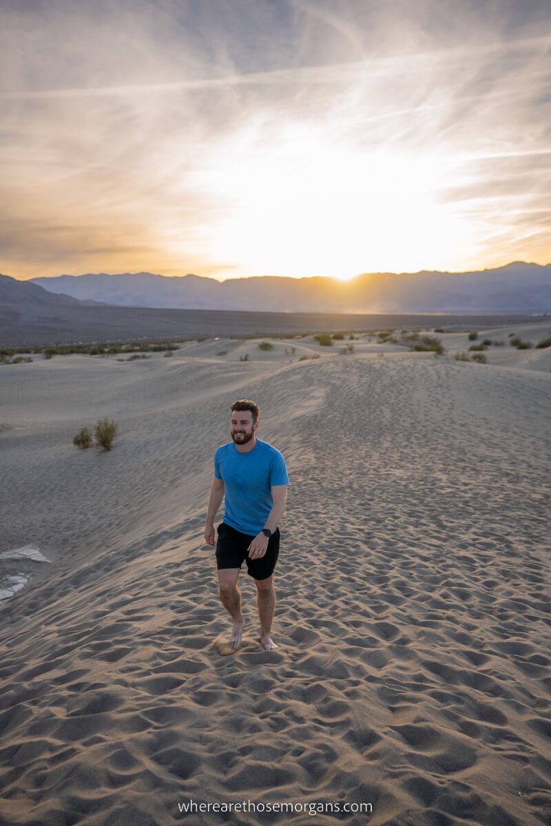 Man walking on sand dunes at sunset in shorts and t shirt