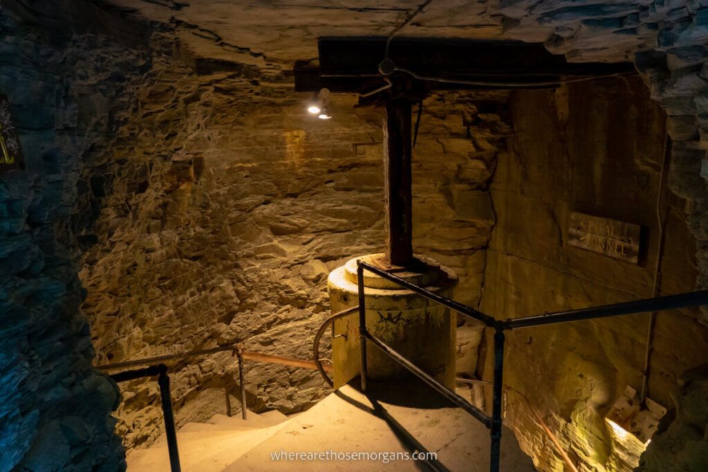 A spiral staircase inside a cave with metal frame and orange light