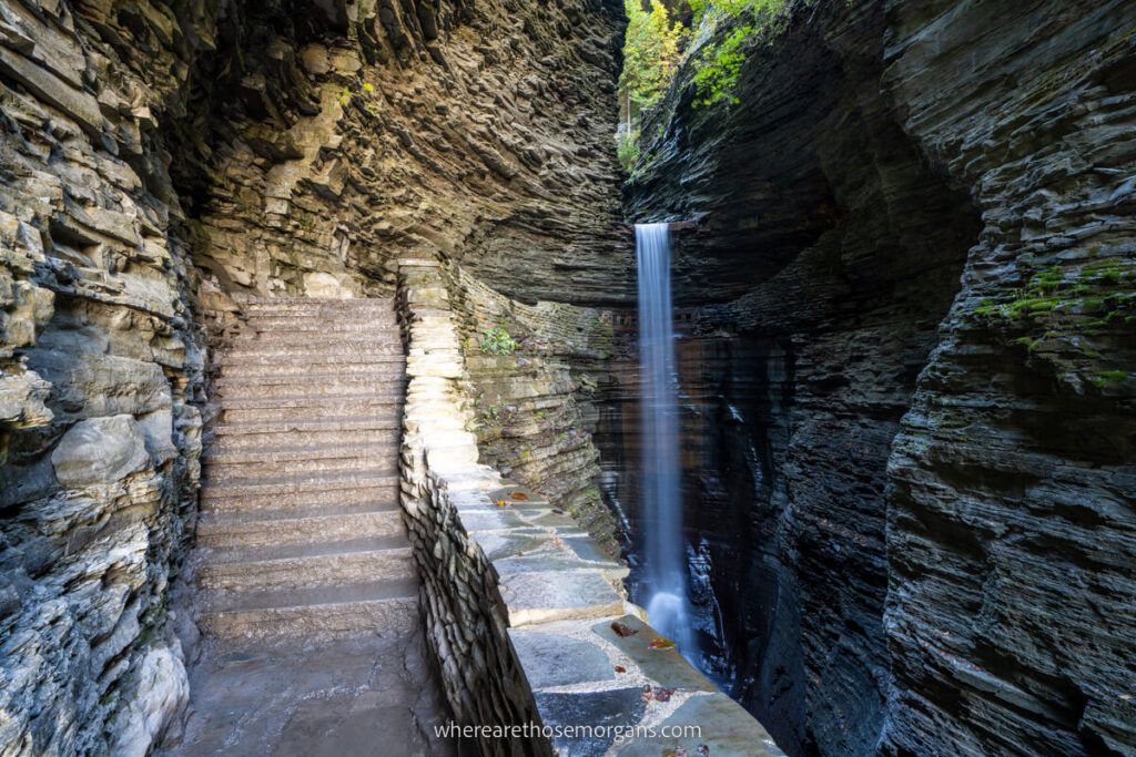 Cavern Cascade waterfall in Watkins Glen State Park Gorge Trail stone staircase and thin waterfall with sunlight