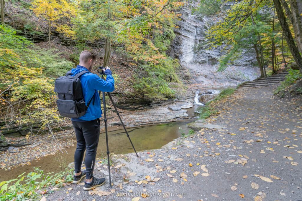 Man standing with a tripod of take a photograph of a waterfall