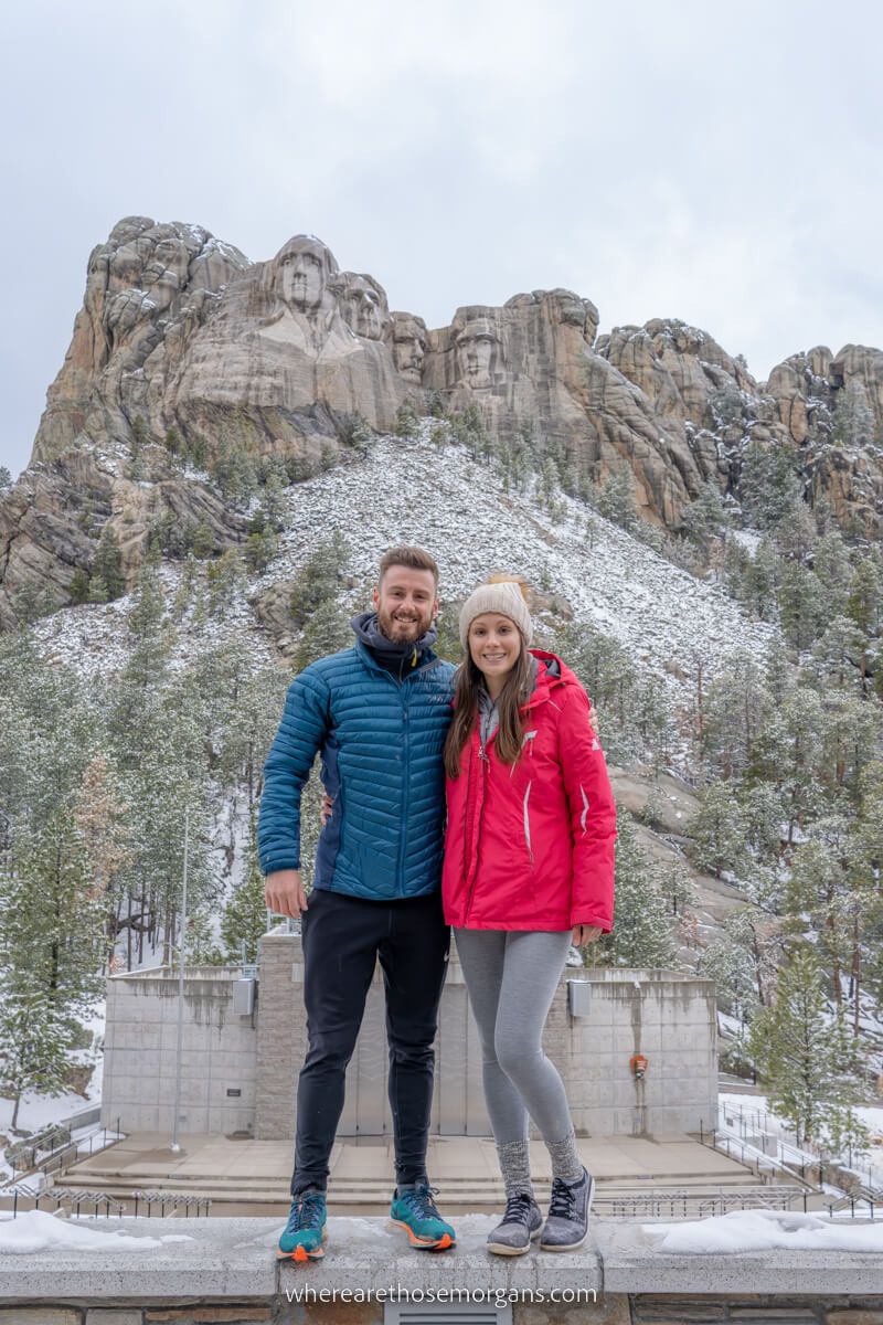 Couple standing on a wall in front of Mount Rushmore perspective photo