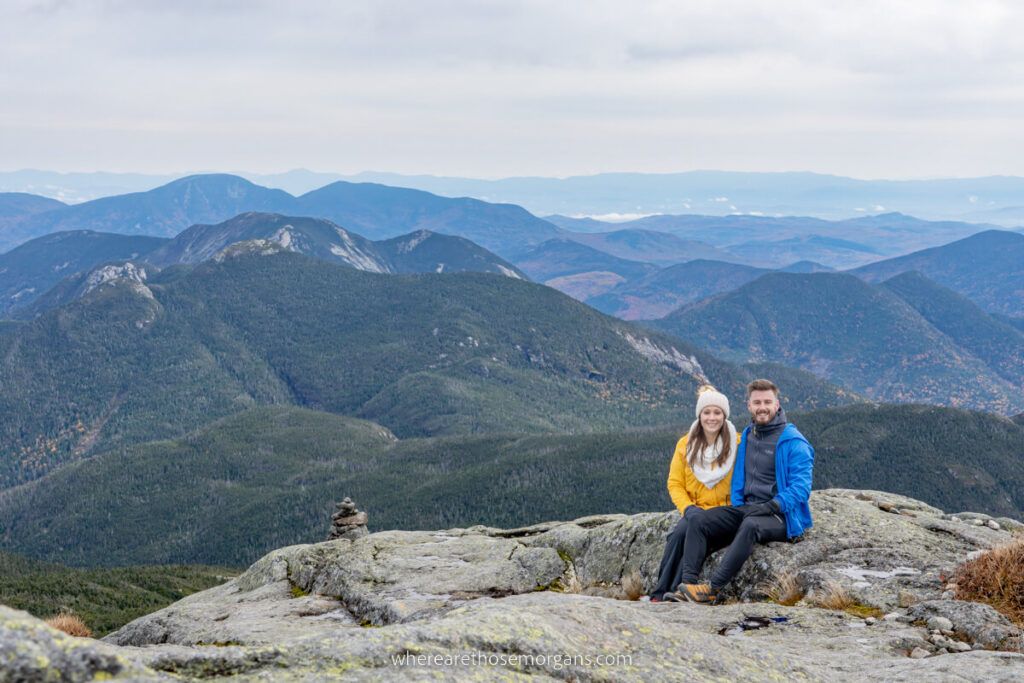 Man and woman sitting at the summit of Mount Marcy