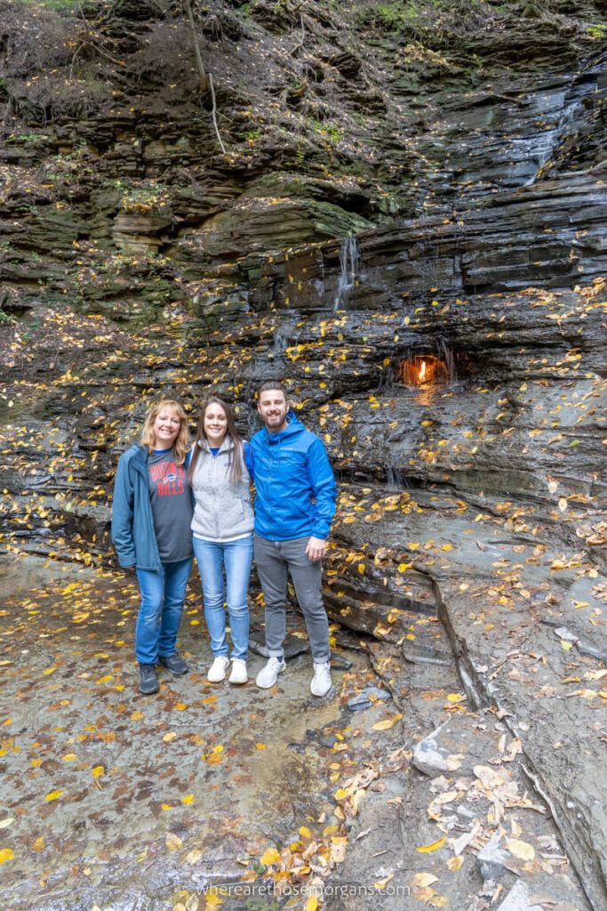 Three people posing for a photo with Eternal Flame Falls