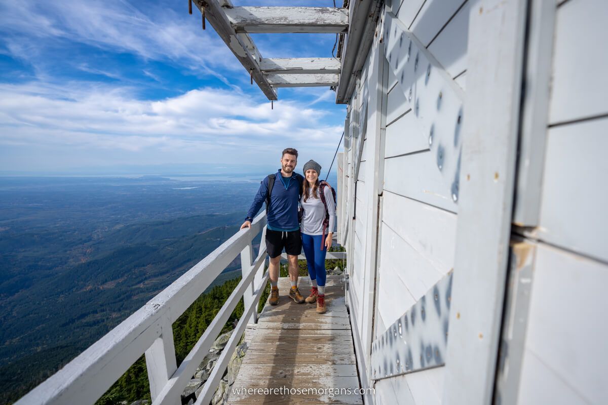 Couple on a hike in Washington State USA standing on the side of a wooden fire watchtower with far reaching views