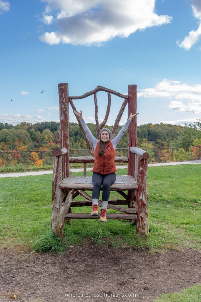 Woman sitting on Letchworth State Park's large wooden chair near the Mount Morris Dam