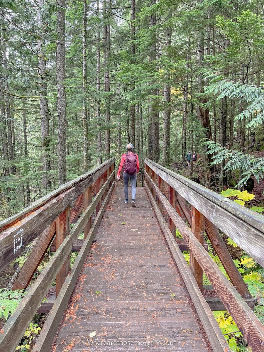 Hiker crossing a wooden bridge next to a creek in Washington