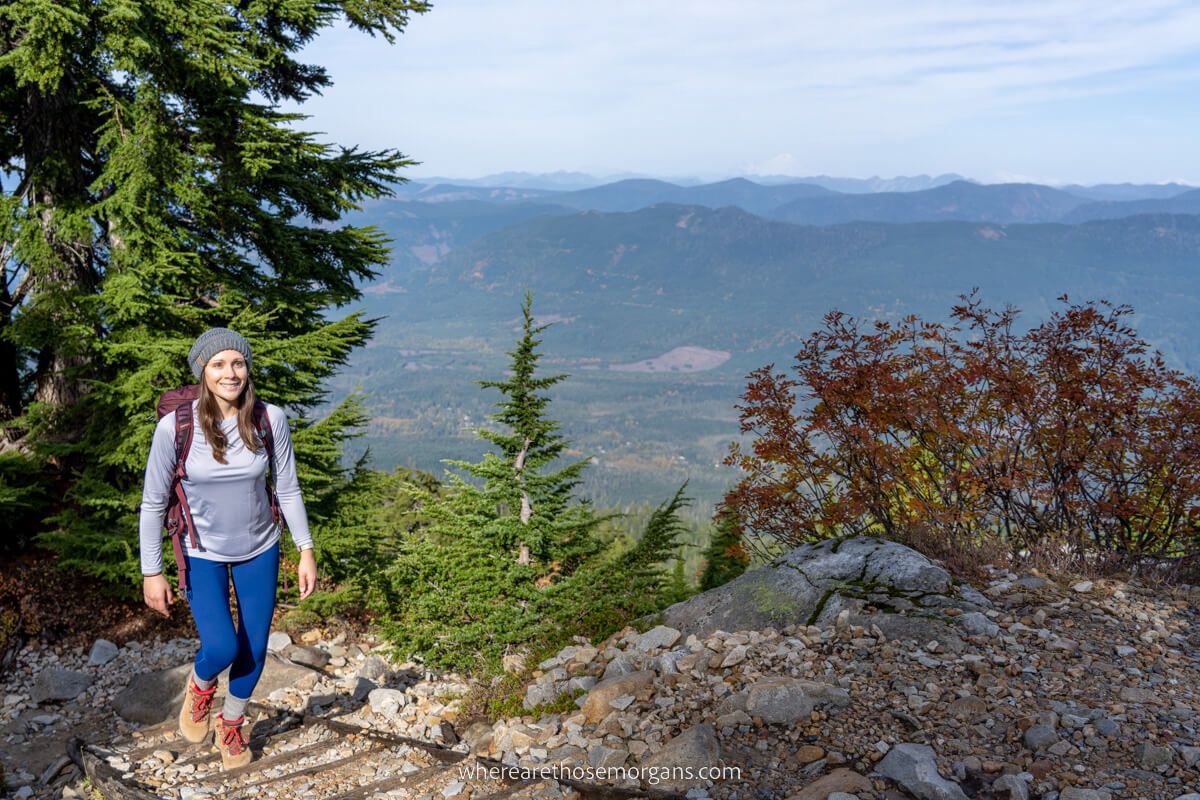 Hiker walking on trail with trees and far reaching views in the background Mt Pilchuck Trail in Washington