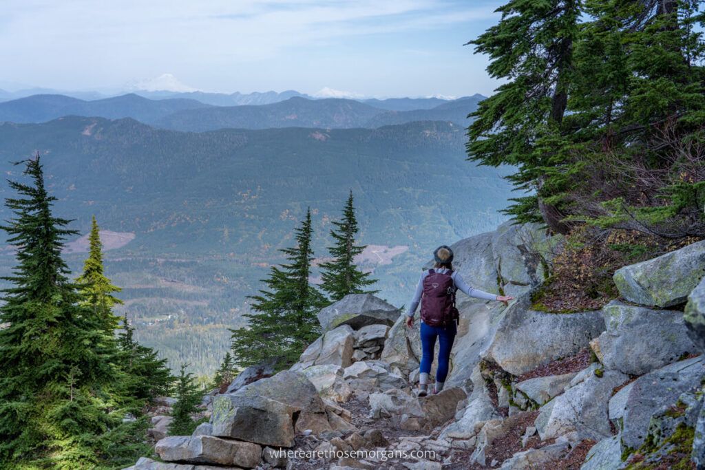 Hiker descending Mount Pilchuck Trail with views over volcanoes in Washington skyline