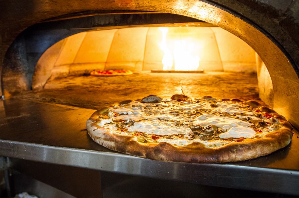 A neapolitan pie sitting outside of a pizza oven