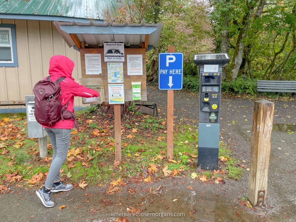 Hiker in waterproofs paying for parking at a lot in Washington State