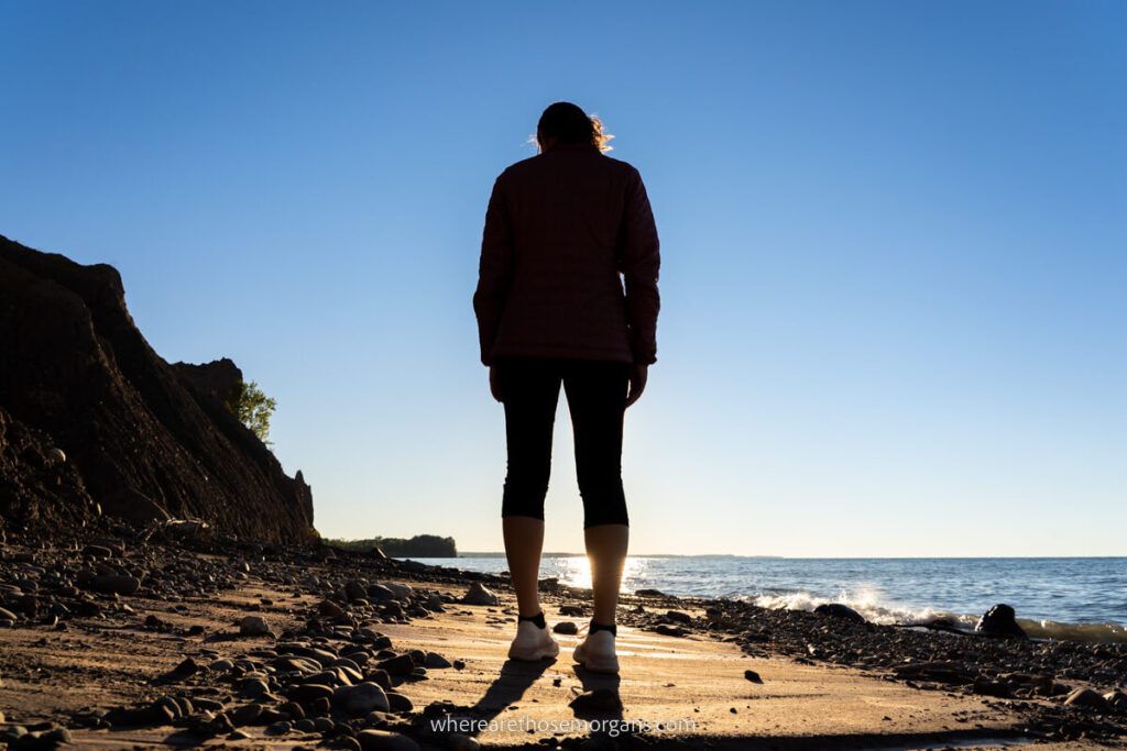 Silhouette of a woman walking along the shore