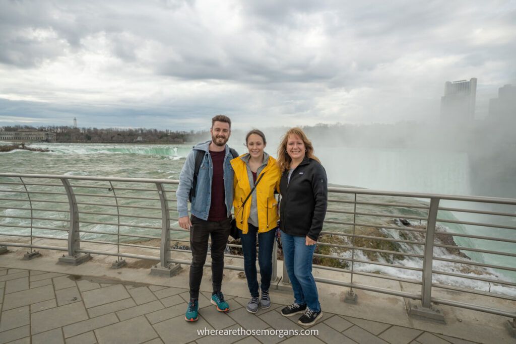 Three people posing for a photo in front of Niagara Falls