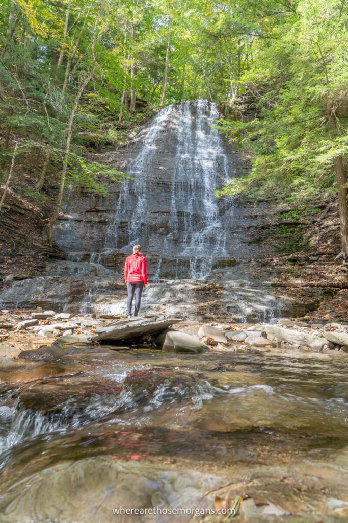Woman standing underneath the first waterfall in Grimes Glen Park
