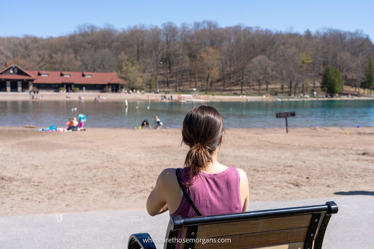 Woman sitting on a wooden bench at Green Lakes State Park near the beach