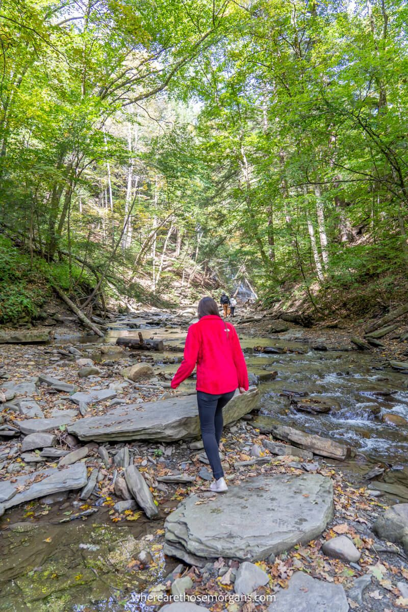 Woman walking over a large boulder in Grimes Glen Park near Naples NY