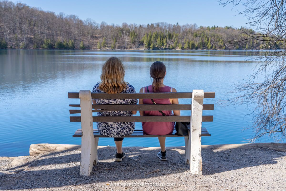 Two people sitting on a wooden bench at Round Lake in Green Lakes State Park