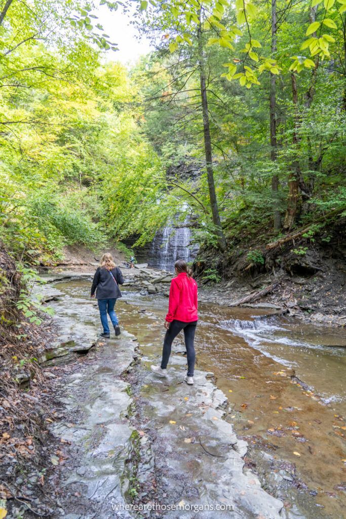 Women walking through Grimes Glen Creek to get to the second waterfall in the park