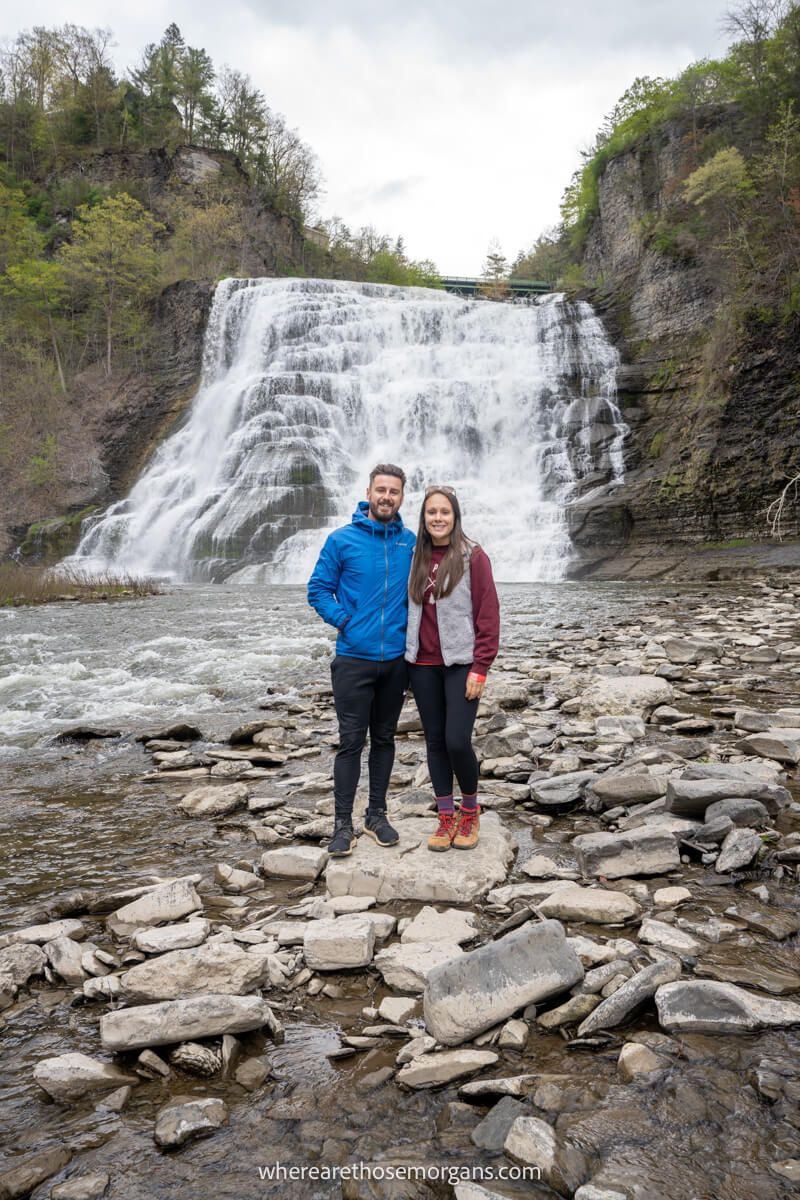 Couple in a photo in front of Ithaca Falls in new york state on a cloudy and cold day