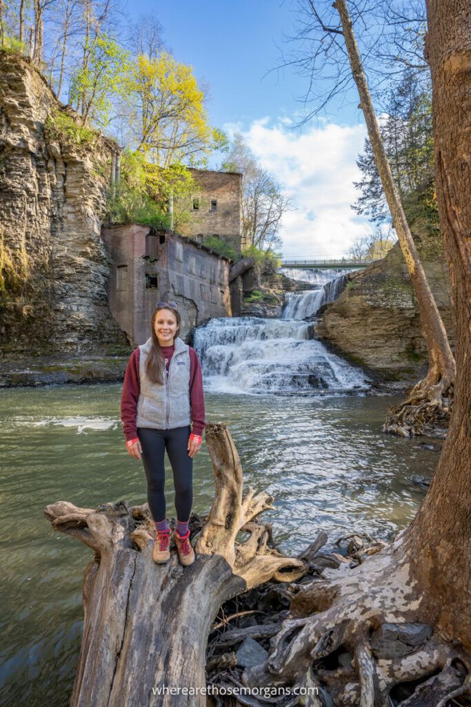 Woman standing on a log in front of Wells Falls near Ithaca